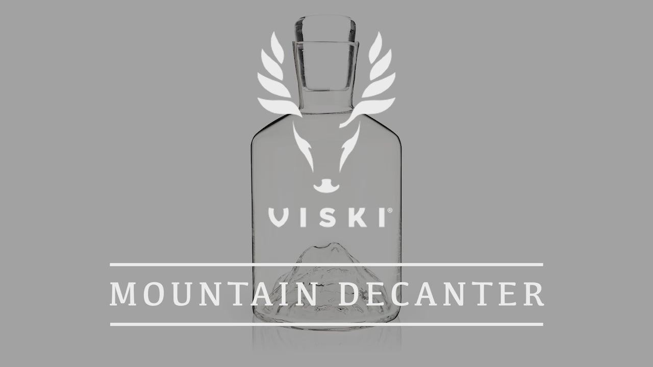 Load video: Close-up of Viski Mountain Decanter and glasses showcasing the intricate mountain design at the base, followed by a detailed shot of liquid being poured, highlighting the craftsmanship and quality of the glassware.
